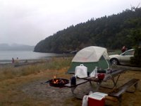 Pic-06202013-010  Yup - really starting to rain now, but the fire is going strong thanks to charcoal. You really can't go wrong with MatchLight. I love my water jug, too, sitting on the table. Means you always have water handy. This campground only had pit toilets - not so fun. No way to wash hands and Ben was afraid of falling in.